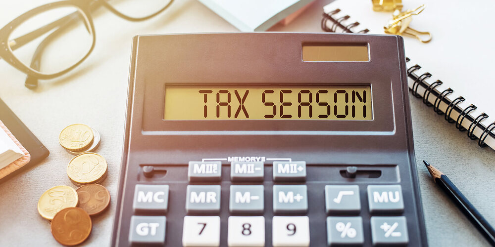 Calculator sits on a desk, spells out the words Tax Season on its screen