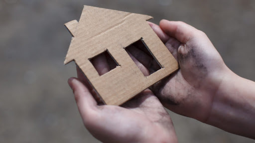 Hand holding cardboard cutout of house